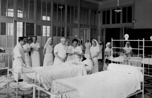Visite du Dr Laurier entouré par les élèves sages-femmes lors des examens des femmes enceintes dans une salle de la maternité, 1936.